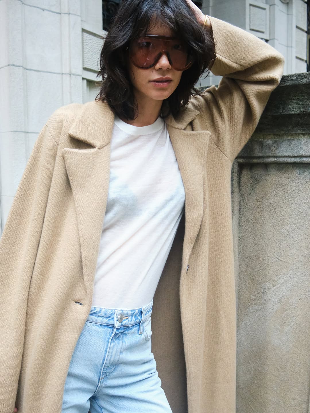 A long, oversized coat in a warm butterscotch or camel color. It features wide notch lapels and appears to be made of a soft, textured material like cashmere.