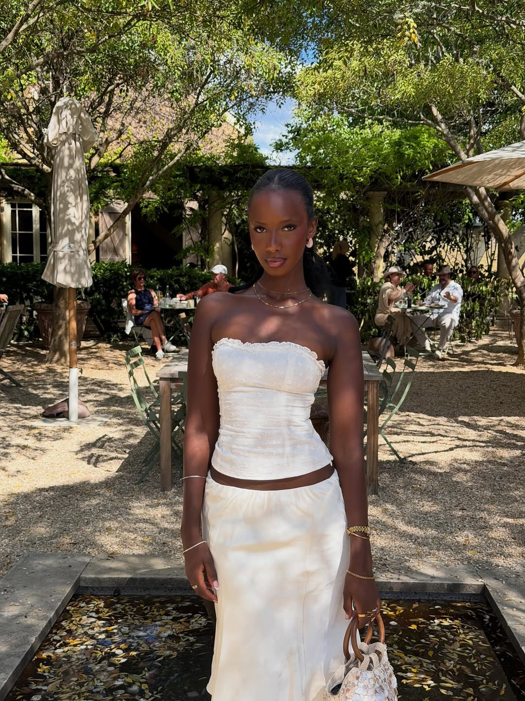 White strapless bustier top with a textured, subtly patterned fabric. It features ruching along the bodice and delicate ruffled trim at the straight neckline.