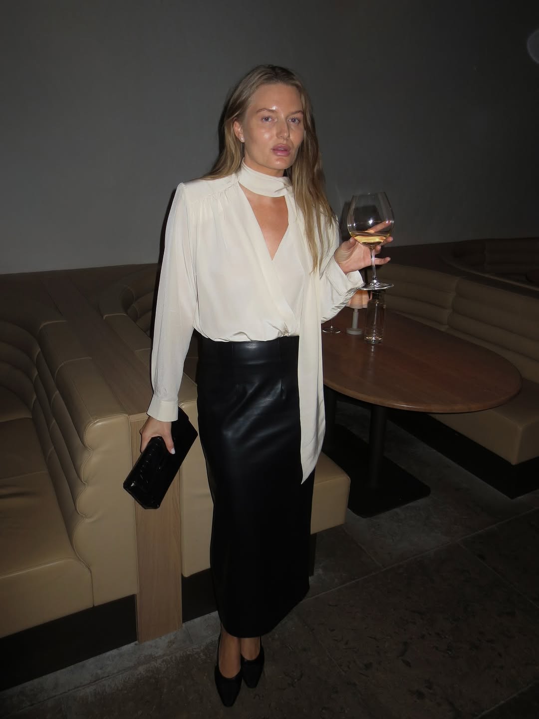 A black, high-waisted midi-length pencil skirt made of a smooth leather or faux-leather material.