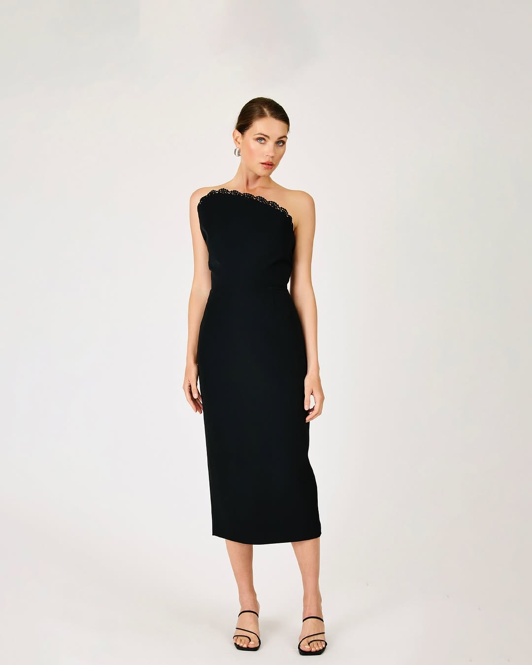 Black one-shoulder midi dress with a lace trim along the neckline and a fitted silhouette.