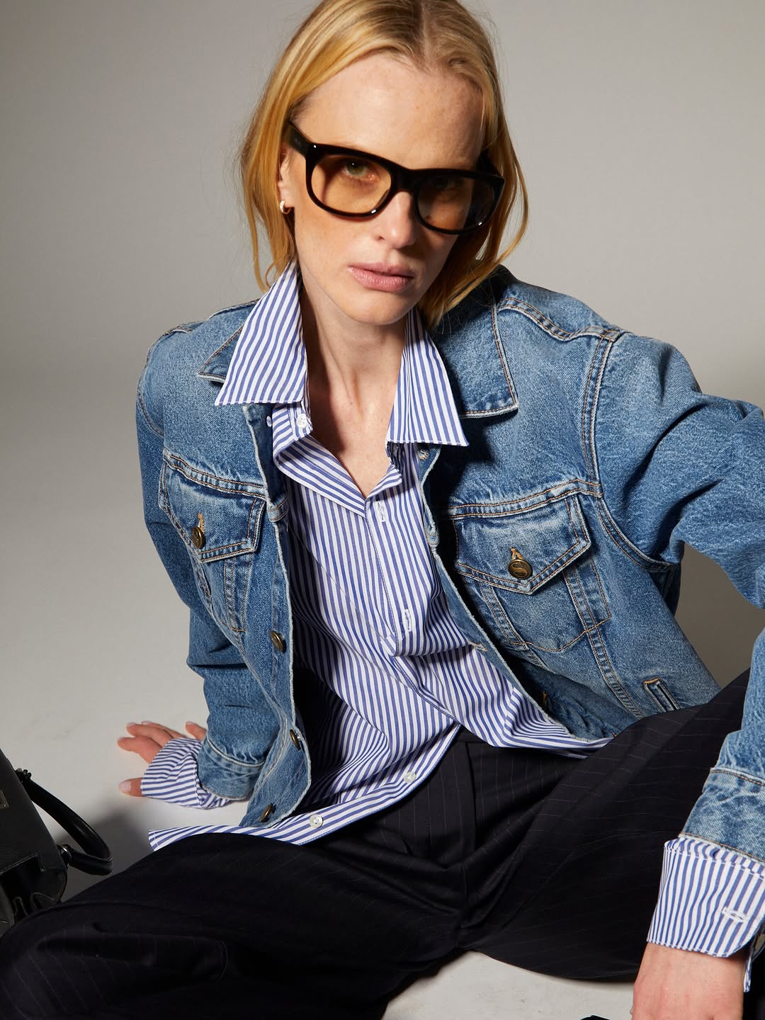 A light-wash blue denim trucker jacket with classic chest pockets featuring buttoned flaps, metal buttons down the front, and contrast stitching.