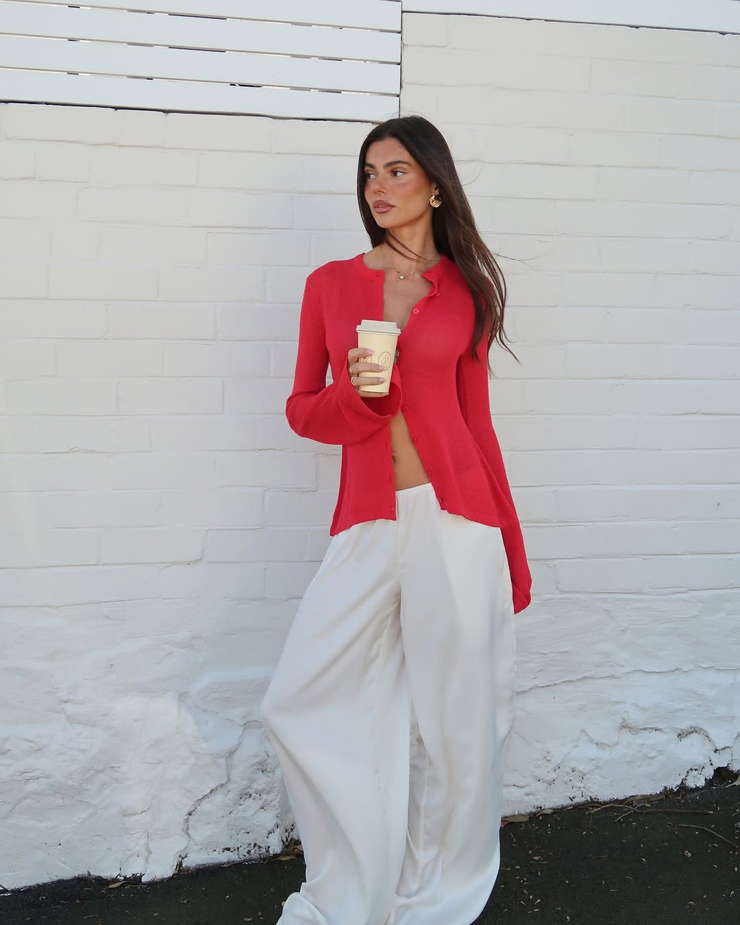 A bright red, long-sleeved cardigan with a lightweight ribbed knit texture. It features a round neckline and small buttons down the front placket.