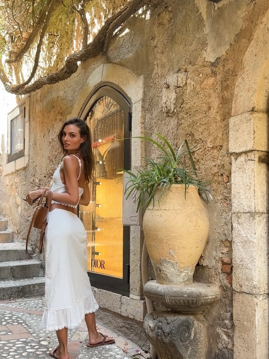Full-body side view of a model wearing a white lace-trimmed crop top and matching tiered midi skirt.