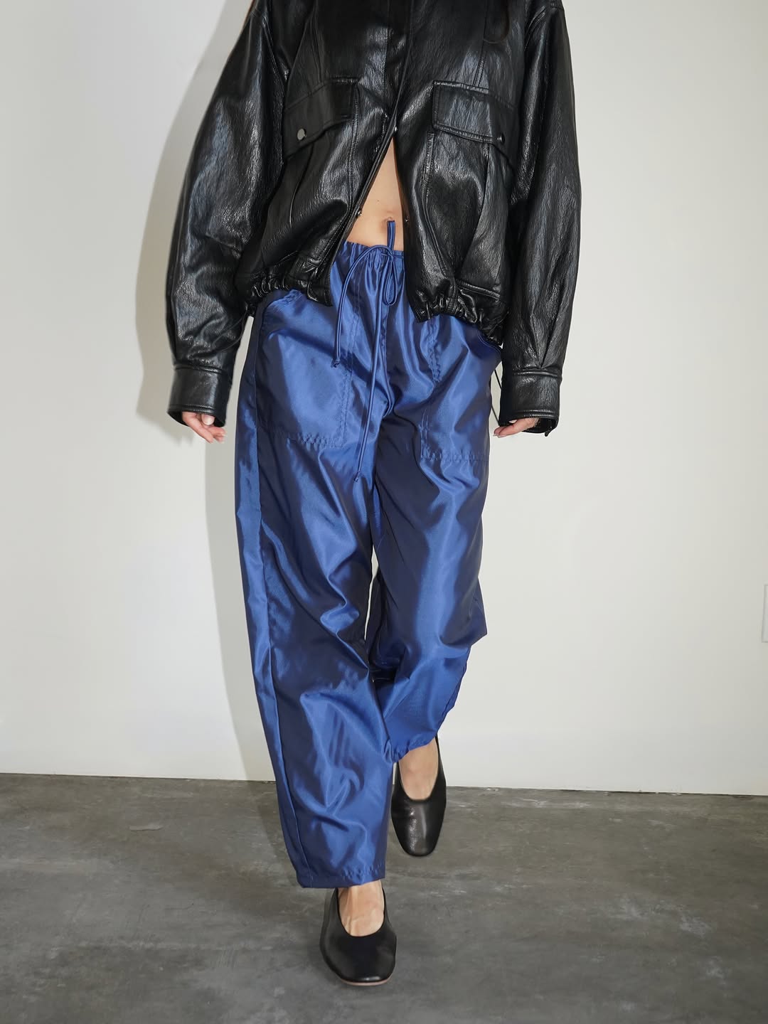 Model wearing royal blue satin pants with a black leather jacket.
