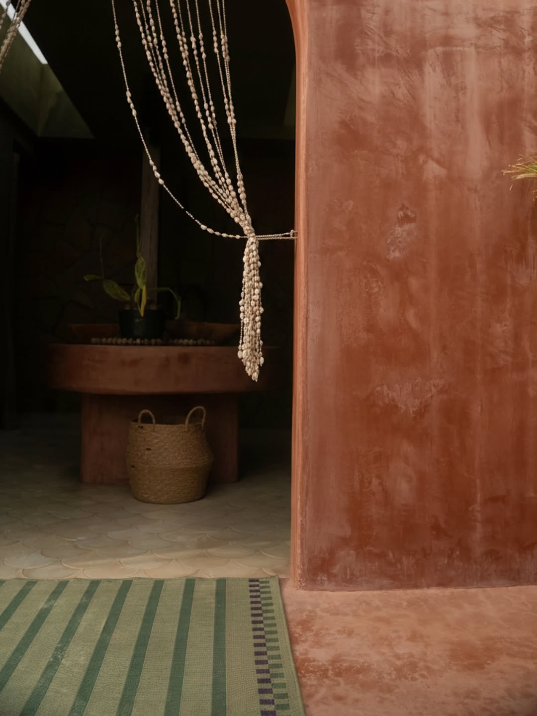 Interior scene featuring terracotta walls, a beaded curtain, and a woven basket.