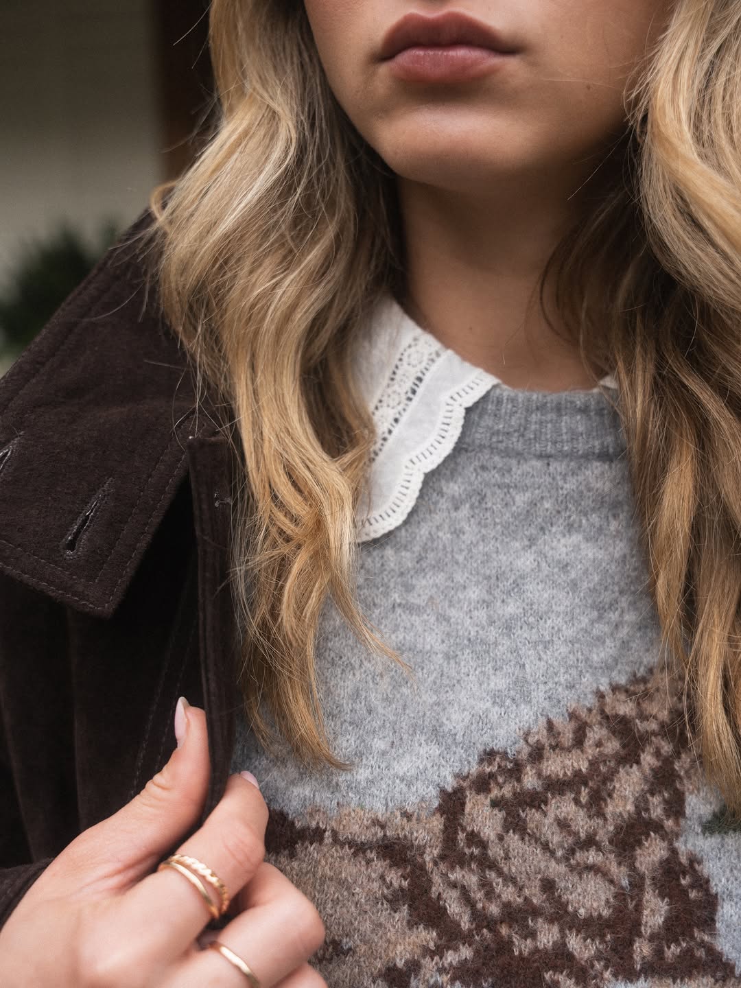 A heather grey crewneck knit sweater featuring a brown and tan Fair Isle or jacquard pattern across the chest.