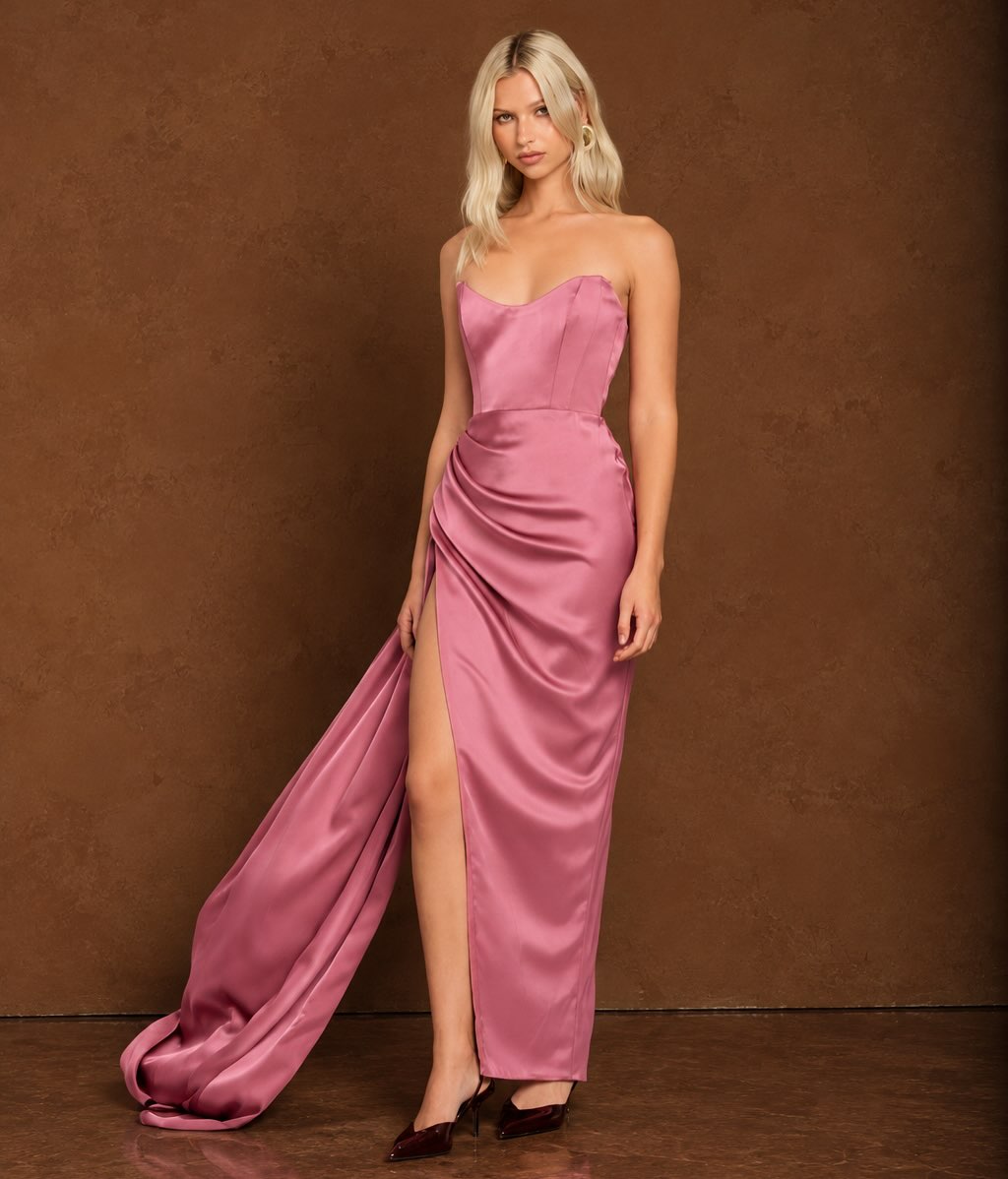 A strapless, floor-length rosewood satin gown featuring a structured sweetheart bodice with visible boning. The skirt is form-fitting with extensive ruching and draping across…