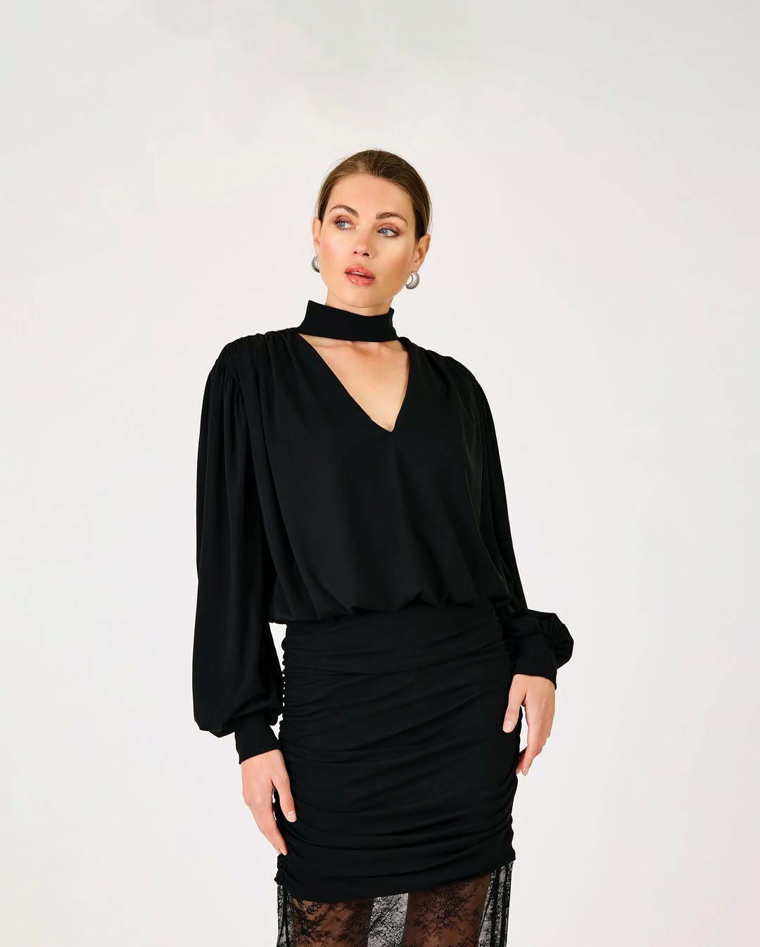 A black long-sleeved top with a deep V-neckline, featuring an attached choker-style neckband and voluminous bishop sleeves gathered at the cuff.