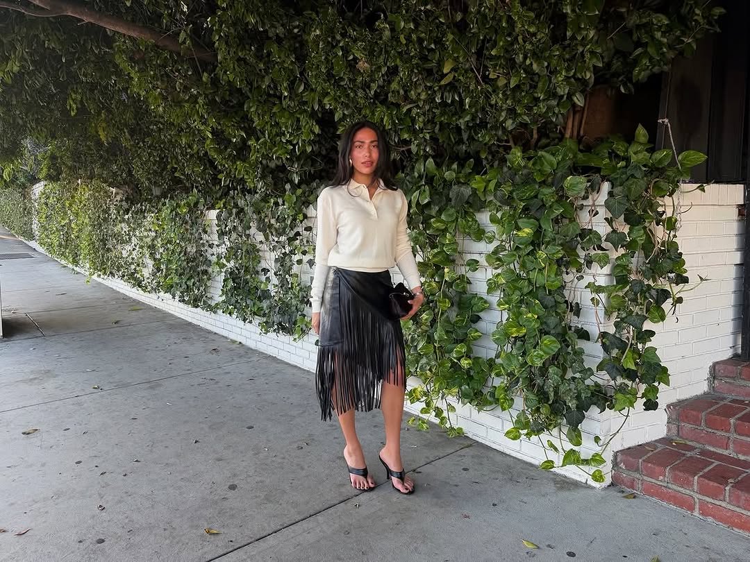 A black leather midi skirt with long fringe detailing on the front.