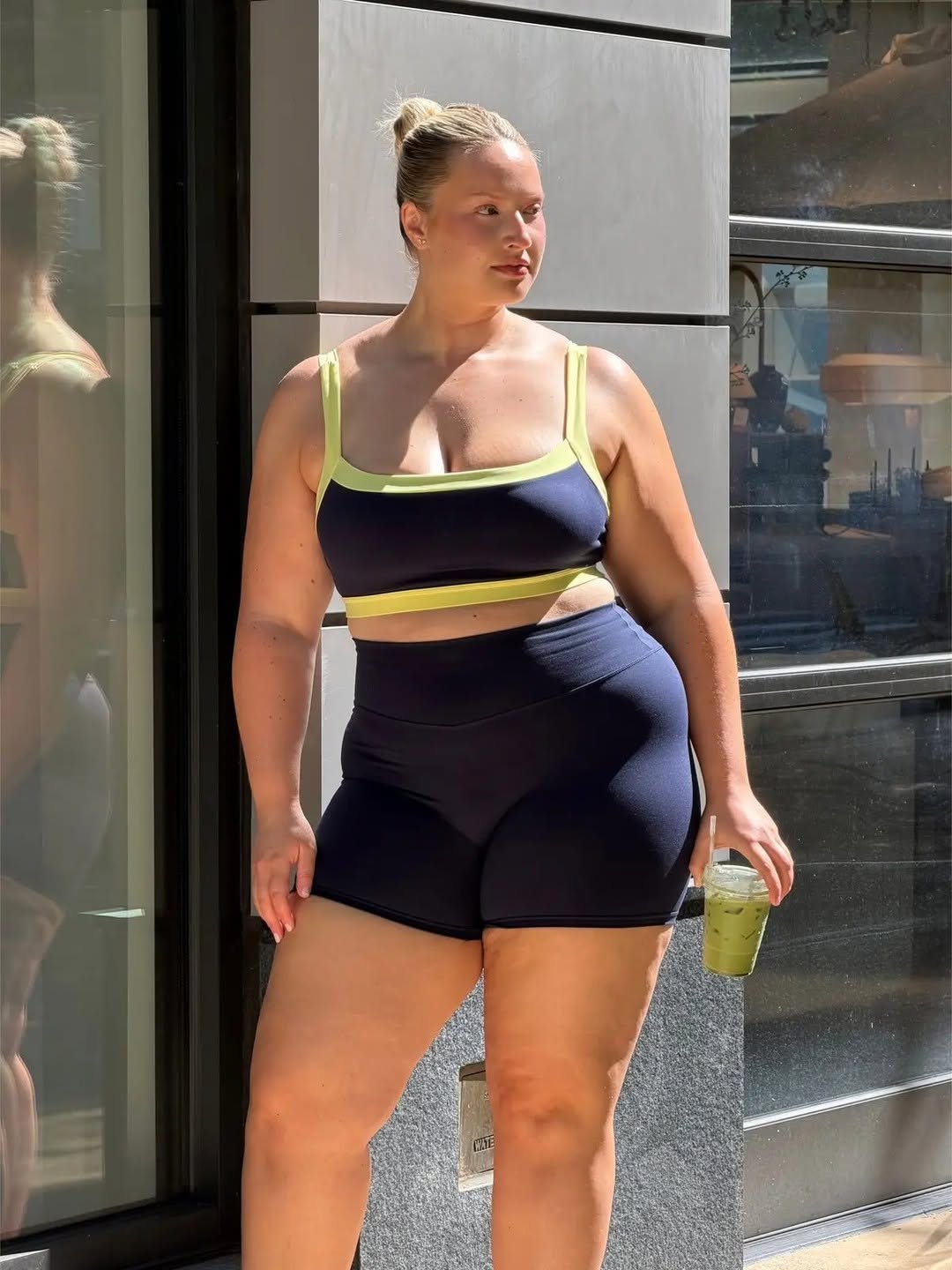 Model wearing navy straight neck bra with yellow trim and navy core shorts.