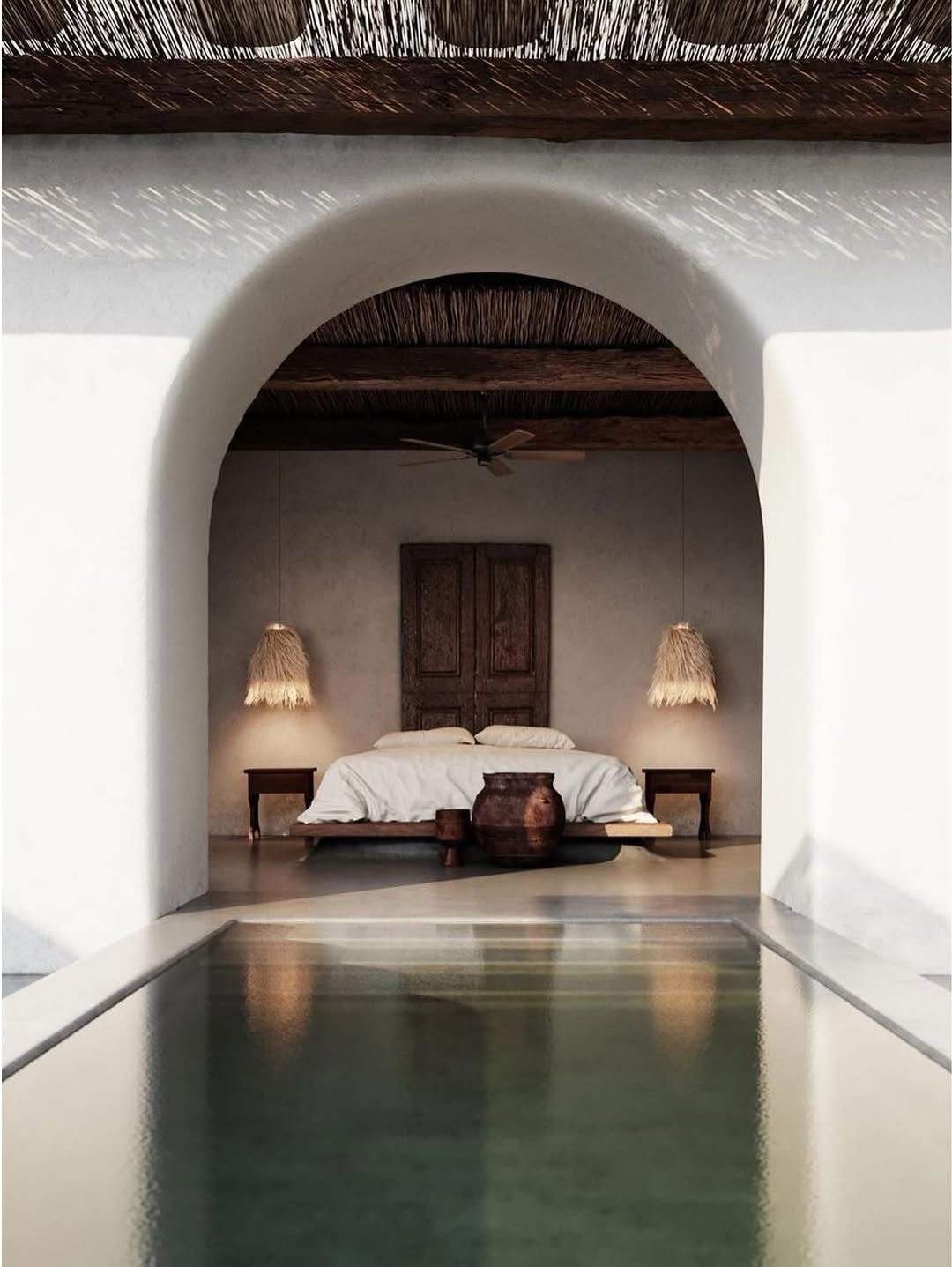 Interior view of a bedroom with a thatched roof and pool in foreground.