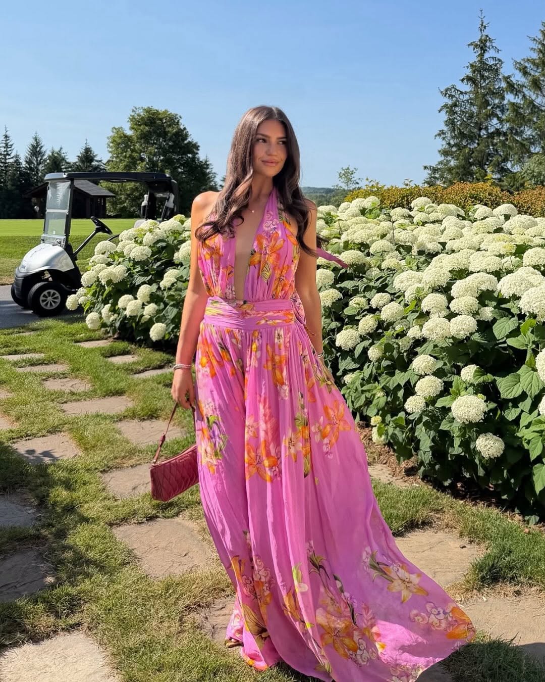Model wearing a pink halter-neck maxi dress with orange and yellow floral print, featuring a deep V-front.