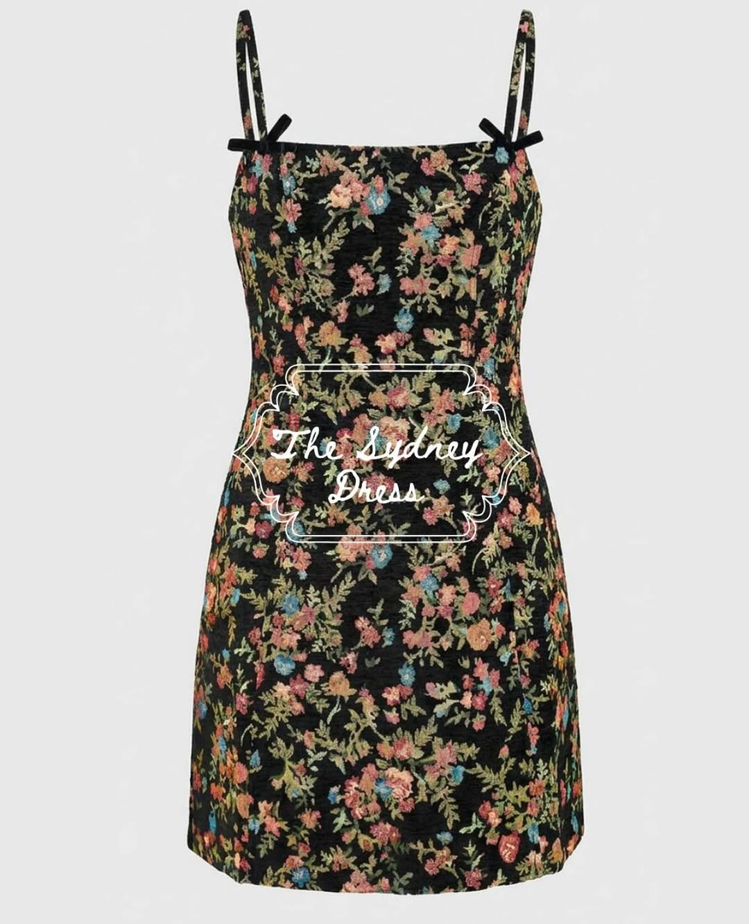 Front view of a black mini dress with colorful floral tapestry print and spaghetti straps.